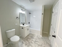 White bathroom space with white and gray marble floor. Doors and vanity are white.