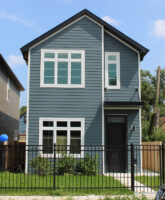 Two-story home with a small front yard and black gate.