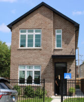 Two-story home with a small front yard and black gate.