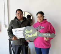 Couple smiling while the woman is holding a large key cut out and the man is holding a certificate.