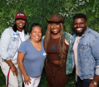 Four staff members smiling and standing in front of a green foilage backdrop.