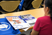 Tight shot of a woman in class looking at a financial wellness packet on the desk in front of her.